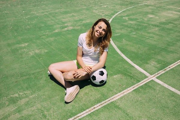 Happy teenager with ball football pitch