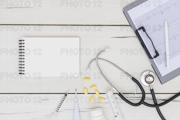 Blank spiral notepad medical equipment s stethoscope ecg report clipboard wooden desk