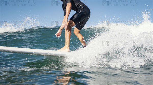 Young man surfs ocean clear water waves