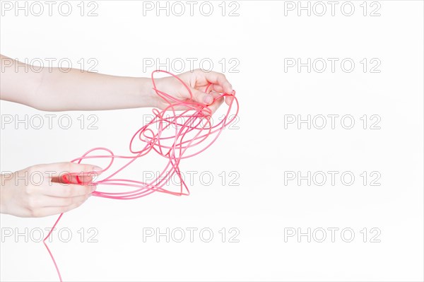 Human hand trying untangle red wire white background