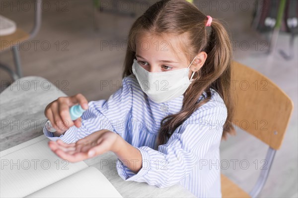 High angle kid disinfecting her hands