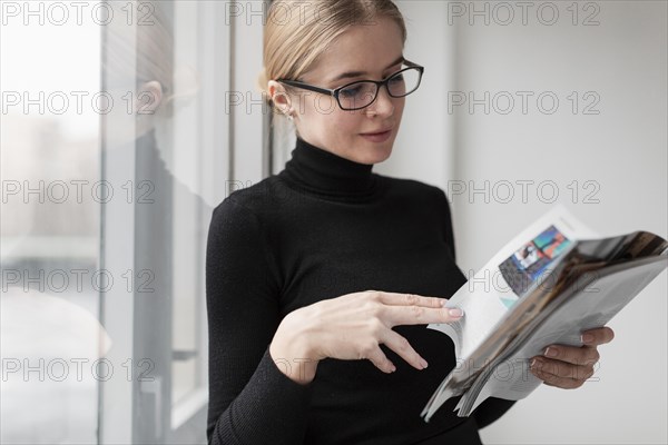 Side view young female reading magazine