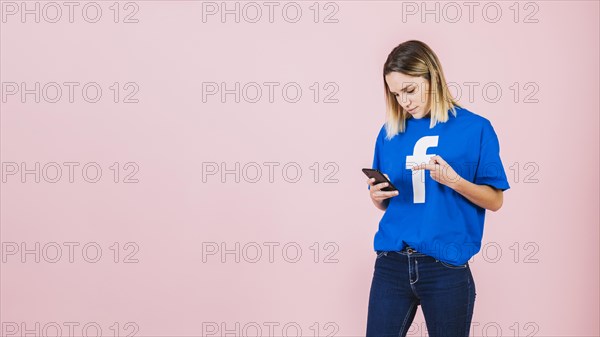 Young woman pointing mobile phone pink background