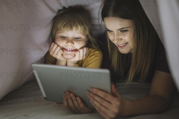 Smiling sisters watching movie blanket