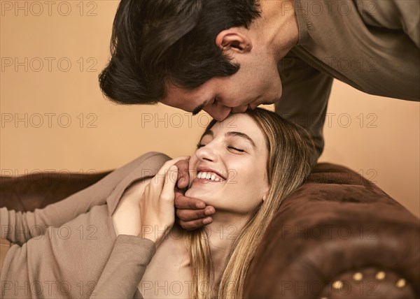 Side view man kissing happy woman forehead