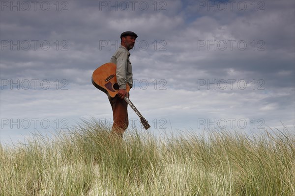 Man with guitar in the dunes