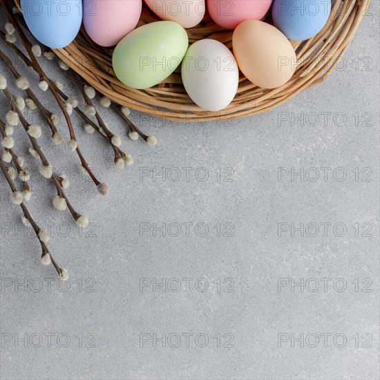 Top view colorful easter eggs basket with flowers copy space