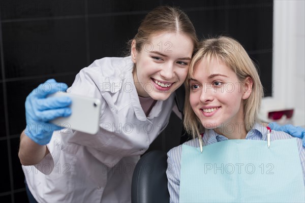 Happy dentist taking selfie with patient