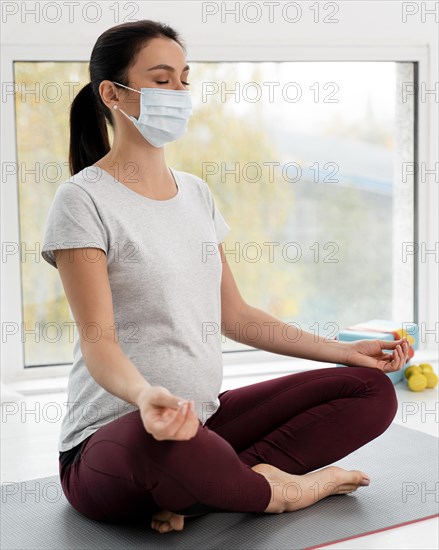 Pregnant woman with medical mask doing yoga