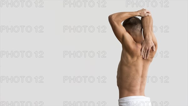 Shirtless man stretching his arms with copy space