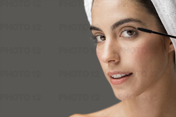 Woman applying mascara her lashes