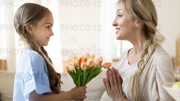 Daughter giving mother bouquet tulips as gift