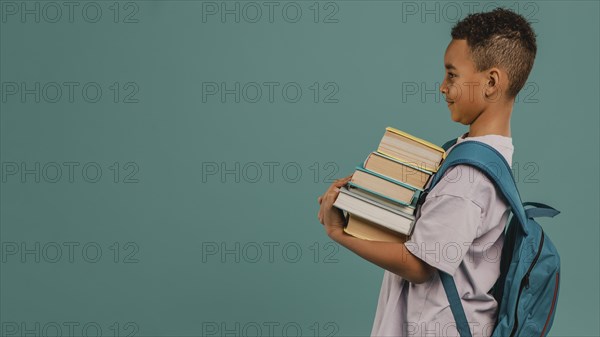 Side view child holding pile books