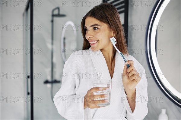 Young woman holding toothbrush glass water