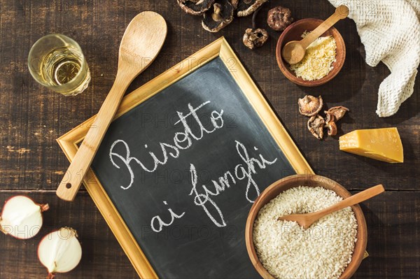 Overhead view ingredients making risotto funghi written slate with chalk