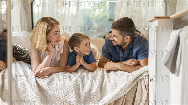 Happy family spending time bed caravan