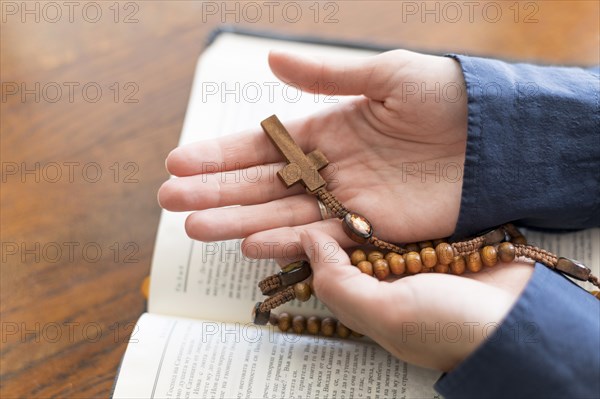 High angle person holding rosary with holy book open