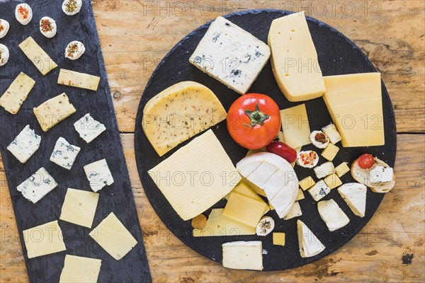 Cheese platter with tomatoes mini sandwich black slate wooden table