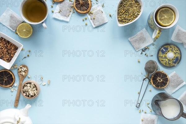 Elevated view lemon tea herbs milk strainer dried chinese chrysanthemum flowers teapot teabags arranged blue background