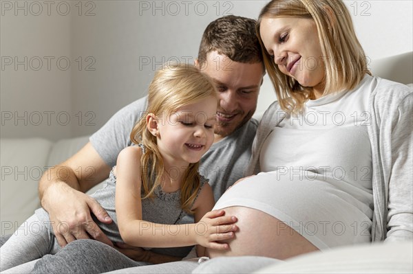 Beautiful little girl touching mother belly