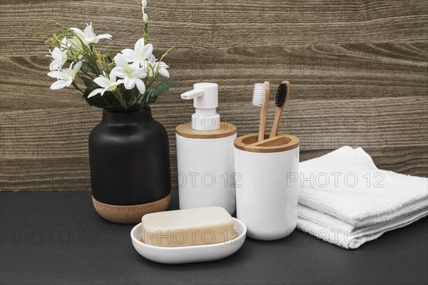 Soap toothbrush cosmetic bottle towel white flower vase black surface