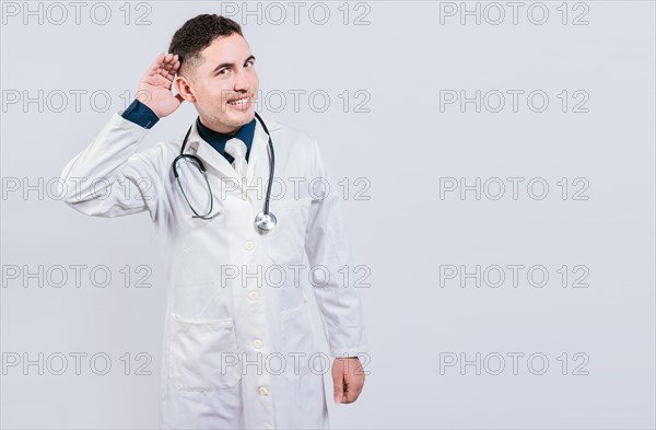 Cheerful doctor listening to a rumor. Latin doctor smiling with hand over ear isolated