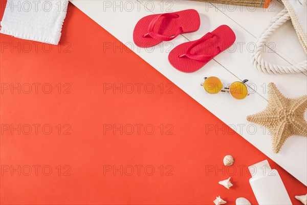 Flip flops near towel with starfish bottle with sunglasses among seashell