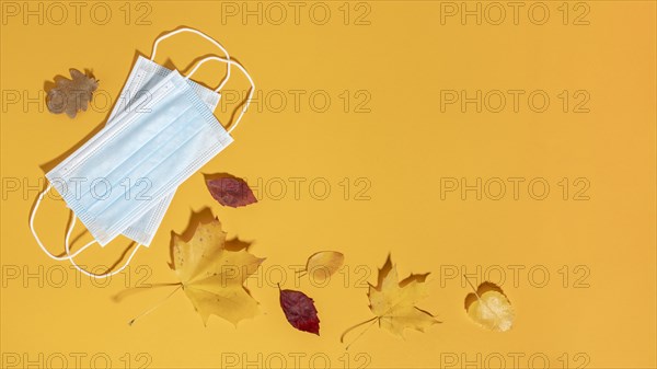 Flat lay medical masks with autumn leaves copy space