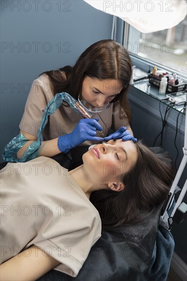 Beautician doing eyebrow treatment her female client