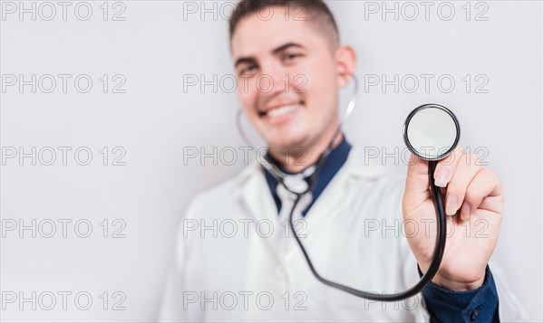 Happy young doctor holding stethoscope looking at camera. Portrait of latin doctor holding stethoscope isolated