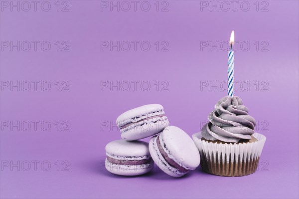 Macaroons near cupcake with candle
