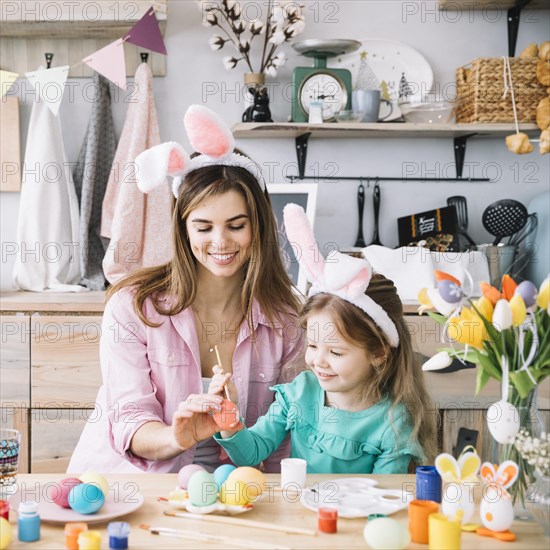 Mother daughter painting eggs easter table