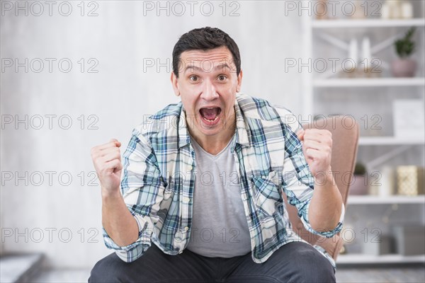 Man crying showing fists chair home
