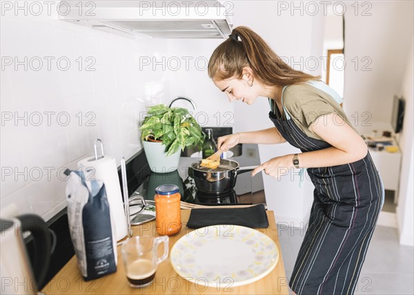 Young woman boiling rigatoni pasta sauce pan electric stove