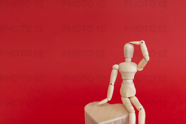 Wooden mannequin sitting wooden heart