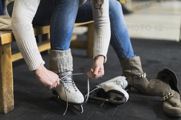 Crop woman putting ice skates