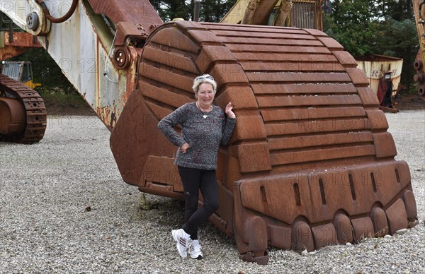 Woman standing in front of an excavator shovel