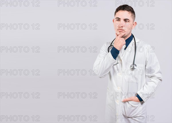 Pensive doctor man looking up. Young doctor thinking and looking up isolated