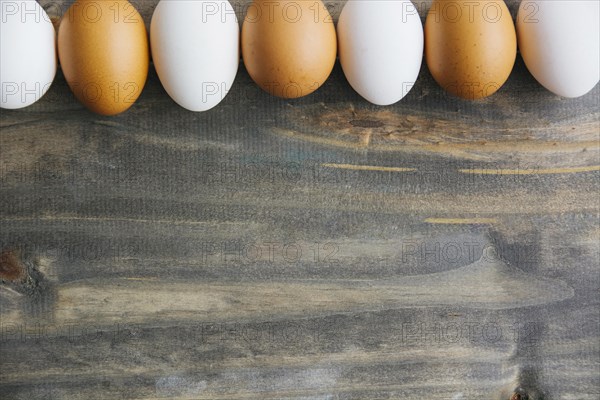 Row brown white eggs wooden background