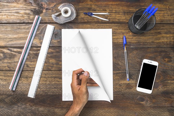 Overhead view person turning page with stationery mobile phone table