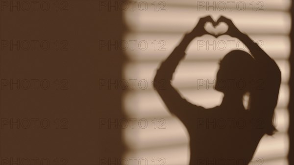 Shadow woman making heart