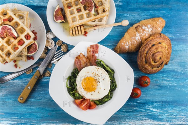 Waffles with fig baked pastries egg fried egg white plates blue textured backdrop