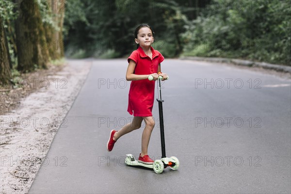 Little girl riding push scooter road