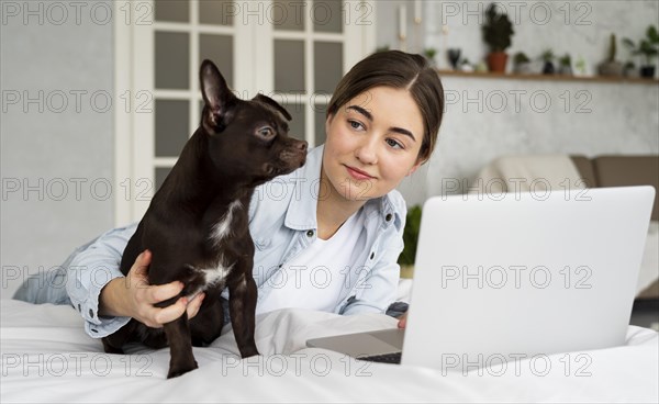 Medium shot teen bed with laptop dog