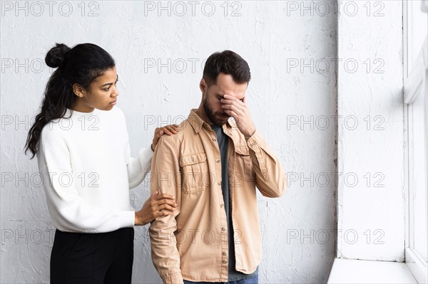 Sad man being consoled by woman group therapy session