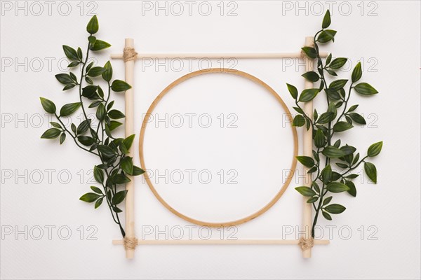 Wooden square circle frame decorated with green leaves white backdrop