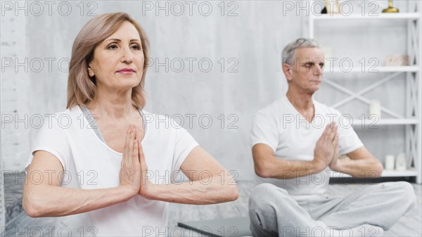 Healthy old couple sitting lotus pose with praying hands