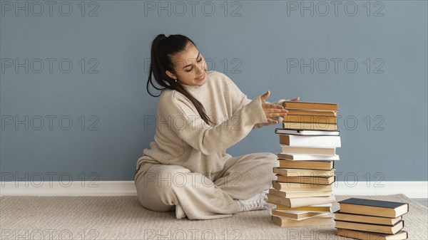 Full shot woman stacking books