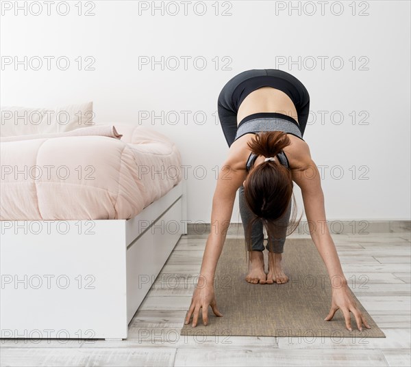 Full shot woman stretching mat home