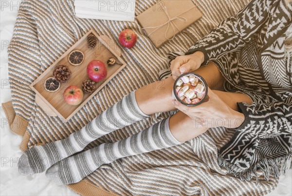 Woman with hot chocolate relaxing bed